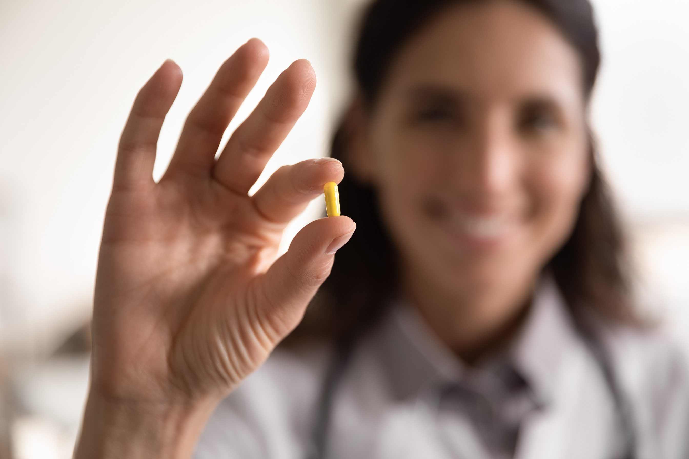 Smiling female pharmacist looking at camera presenting new effective pill